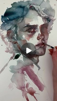 a person is drawing with watercolors on paper and has a pencil in his mouth