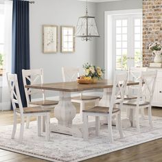 a dining room table with white chairs and an area rug