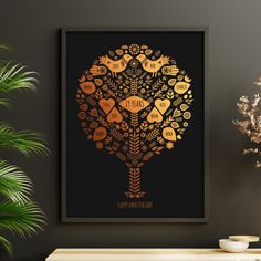 a black and gold art print on a wall above a table with potted plants