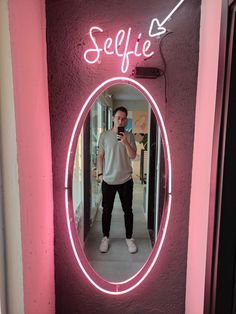 a man standing in front of a mirror with the word selfie written on it