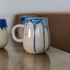 two white and blue mugs sitting on top of a wooden table