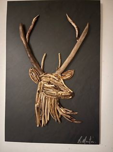 a deer head made out of driftwood on a black board with white walls and flooring