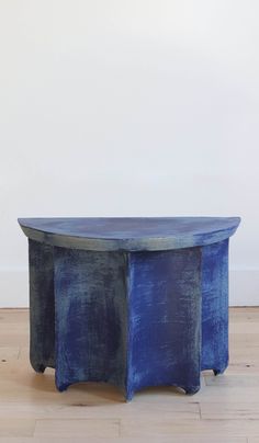 a blue table sitting on top of a hard wood floor next to a white wall