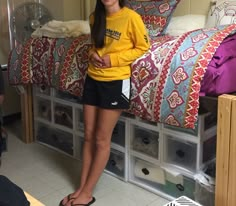 a young woman standing in front of a bed