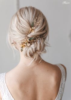 a woman with blonde hair in a low bun wearing a gold leaf and flower headpiece