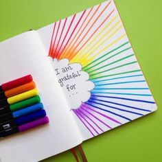 an open notebook with colored crayons on it and the words i am grateful for