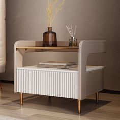 a white table with a book and vase on it next to a couch in a living room