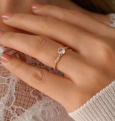 a woman's hand wearing a gold ring with a diamond on it and a white lace