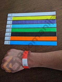 a person's arm and wristbands on top of a table with colored strips