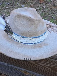 An absolutely stunning, custom burned horseshoe with wildflowers. This hat is a beautiful cream felt with beautiful accents of bluejean and lace along with an exotic feather! This would be a great addition to any outfit whether you dress up or down! Bohemian Felt Hat With Flat Brim For Kentucky Derby, Bohemian Felt Hat For Rodeo, Bohemian Brimmed Felt Hat For Kentucky Derby, Bohemian Felt Hat For Kentucky Derby With Brim, Bohemian Brimmed Felt Hat For Western-themed Events, Bohemian Felt Hat For Kentucky Derby And Western Events, Bohemian Feather Hat Bands For Ranch, Bohemian Hat Band With Feathers For Ranch, Bohemian Felt Hat For Kentucky Derby