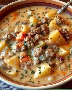 a close up of a bowl of soup with meat and potatoes in it on a table