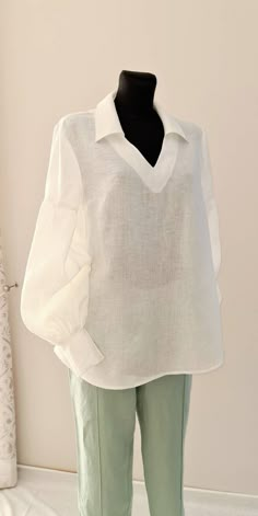 A voluminous A-line blouse, below the hip line.  The neck is V-shaped, with a turndown collar.  Set-in sleeve, single-suture, detachable above the elbow line.  The lower part of the sleeve is assembled at the upper and lower cuts.  The bottom of the sleeve is finished with a stitched cuff with a fastener with 2 serrated loops and 2 buttons.  Front with a middle seam.  Back with shoulder darts.  The bottom line is smoothly rounded. Size chart: SIZE XS (mostly USA/CA-4, UK-6, AU/NZ-8, JAP-7, EU-34 Luxury Padded Bishop Sleeve Blouse, Luxury Cotton Balloon Sleeve Tops, Cheap Blouse With Back Button Closure, Luxury Summer Unstitched Blouse, Luxury Summer Padded Blouse, Three Quarter Sleeve Blouses With Collar Bulotus Top, Luxury Cotton Blouse With Mandarin Collar, Luxury Cotton Blouse For Eid, Oversized Blouse With Blouson Puff Sleeves