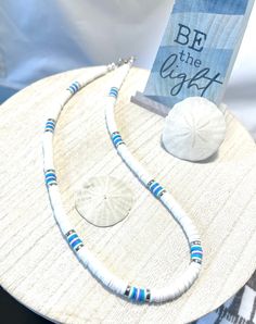 This heishi bead necklace is 18 inches long and closes with a lobster claw clasp. It's a great addition to your summer wardrobe. Adjustable Blue Beachy Necklace, Blue Beachy Necklace, Adjustable White Shell Necklace In Coastal Style, Adjustable White Shell Necklace Coastal Style, Coastal Style White Adjustable Necklace, Adjustable Blue Shell Necklace For Summer, White Beaded Necklaces With Lobster Clasp For Summer, Beach Style Heishi Beads Single Strand Jewelry, Turquoise Heishi Beads Jewelry For Vacation