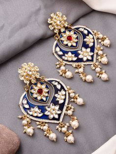 These crescent-moon shaped dark blue kundan earrings are the perfect match for any festive outfit, especially when you want to add that extra hint of glamour! They feature a red centre stone to bring a beautiful contrast to the overall look. The earrings have a push-back closure and are comfortable to wear for long durations.  This earring design is also available in a gorgeous pink and a festive yellow colour to brighten up your outfits! Festive Blue Meenakari Chandbalis, Blue Chandbalis For Festivals And Celebrations, Blue Chandbalis For Celebration Festivals, Blue Chandbalis For Celebration And Festivals, Blue Chandbali Chandelier Earrings For Festivals, Blue Kundan Earrings For Party, Blue Kundan Danglers For Celebration, Festival Blue Kundan Chandbalis, Blue Kundan Chandbalis