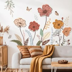 a living room with flowers painted on the wall and a blanket draped over the couch