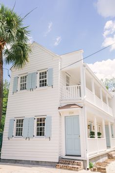 a white house with blue shutters and palm trees