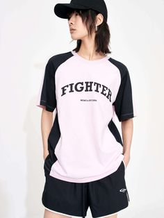 a woman wearing a black and white shirt with the word fighter on it, standing in front of a white wall