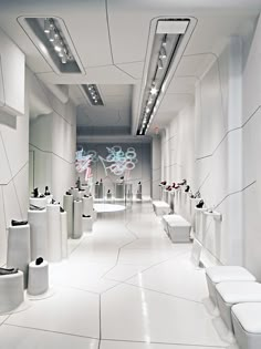 a long white bathroom with many toilets and sinks