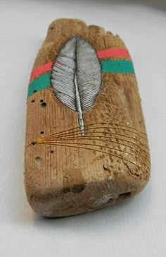 a piece of wood with a feather painted on it's side, sitting on a white surface