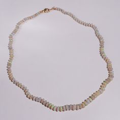 Discover the enchanting beauty of our Australian Opal Knotted Candy Bead Necklace, a stunning piece that captures the mesmerizing play of colors. This 18-inch necklace features smooth opal beads that shimmer with hues of teal, purple, green, and yellow, creating a vibrant and dynamic look. Each bead is meticulously knotted with luxurious lavender silk, enhancing the necklace’s elegance and durability. The opals rest on a cream-white base, providing a perfect backdrop that highlights their natura Opal Jewelry With Polished Beads As A Gift, Polished Round Bead Opal Necklaces, Handmade Opal Bead Necklaces, Polished Round Opal Bead Necklaces, Opal Rondelle Bead Necklace, Handmade Opal Necklaces With Round Beads, Opal Gemstone Beaded Rondelle Necklace, Opal Necklaces With Polished Round Beads, Opal Rondelle Necklace With Gemstone Beads