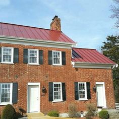 an old brick house with red roof and shutters