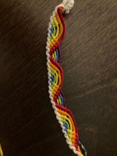 a multicolored bracelet is sitting on a table next to an orange and yellow toothbrush