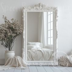 a white bedroom with a large mirror on the wall next to a plant and bed