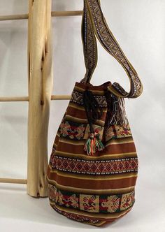 Peruvian Handmade Bucket Style Crossbody Bag in Brown This is a simple and fun handmade bucket bag from Peru.  It is made of lightweight Andean fabric (not thick wool) in a dark brown with designs common to Peruvian style.   Perfect fall colors!  Please note handcrafted items may have stray threads.   Features *Tie closure Specifications *Approximate Dimensions:  14.5" Height | 9" Diameter  Materials *Andean Textile HANDCRAFTED IN PERU Bohemian Large Capacity Pouch Bucket Bag, Brown Bucket Hobo Bag With Adjustable Strap, Casual Brown Bucket Bag, Bohemian Brown Bucket Bag, Brown Festival Backpack, Casual Brown Handmade Shoulder Bag, Casual Festival Bucket Bag, Brown Festival Backpack Bag, Handmade Brown Hobo Bag