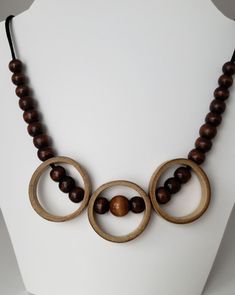 "Bamboo necklace made from salvaged bamboo.  This statement necklace features three bamboo rings with wood beads strung through each ring. Additional wood beads and faux suede cord complete this unique necklace. Necklace length: 24\" Bamboo rings are 1.5\" each Clasp necklace closure. The bamboo is sealed with Mod Podge and finished with clear, acrylic spray." Unique Wooden Beaded Necklaces For Festivals, Unique Round Necklace With Wooden Beads, Bamboo Jewelry Design, Bamboo Necklace Jewelry, Adjustable Wooden Beads Necklace In Nature-inspired Style, Wood Necklace Pendant, Bamboo Necklace, Bamboo Jewelry, Necklace Closure