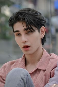 a young man with black hair sitting down