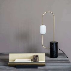 a black and gold table lamp on top of a wooden table next to a white vase