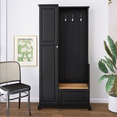 a black armoire in a room with a chair and potted plant next to it