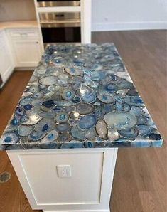 a kitchen counter top with blue and white glass pebbles on the bottom, in front of an oven