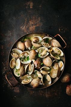 clams in a pan with garlic and parsley on the side, ready to be eaten