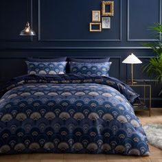 a bed with blue sheets and pillows in a room next to a potted plant