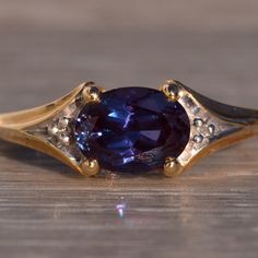 a gold ring with a blue stone in the center on a wooden surface, close up