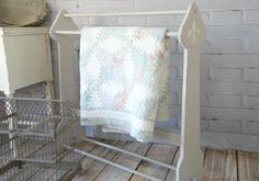 a towel rack with a basket on the floor next to it and a brick wall in the background