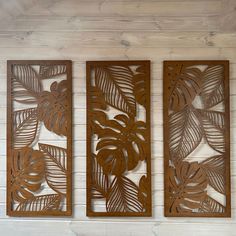 three wooden cutouts with leaves on them hanging on a white wood paneled wall