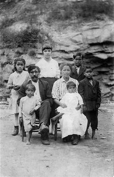 an old black and white photo of a family posing for a picture in front of some rocks