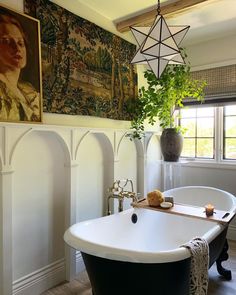 a bathroom with a bathtub, potted plant and pictures on the wall