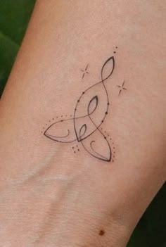 a woman's wrist with a musical note tattoo on the left side of her arm