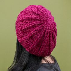 a woman with long black hair wearing a pink knitted beanie on her head