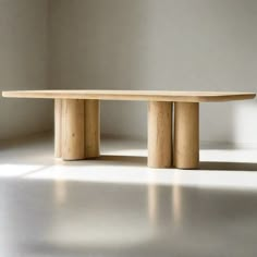 a wooden table sitting on top of a white floor next to a wall and window