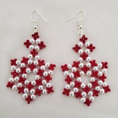 red and white beaded earrings are displayed on a white tablecloth with silver beads