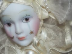 a white mask with gold stars on it's face and pearls around the eyes