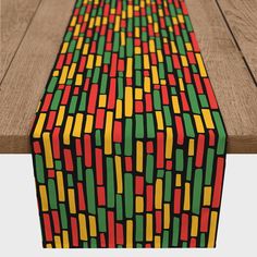 a long table runner with multicolored squares on it and wood flooring in the background