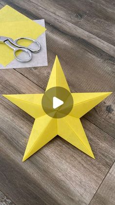 an origami star next to scissors on a wooden floor with paper cut out