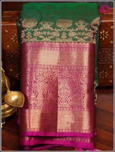 A Kanchipuram silk saree in a lush green shade, featuring intricate floral brocade designs is accentuated with a delicate pink border and pallu. This combination creates a captivating blend of colors and textures. The vibrant green tone symbolize freshness and vitality, while the floral brocade detailing adds an element of traditional charm and elegance. The gentle pink border infuses a soft and feminine touch, completing the graceful and natural aesthetic. Further, the floral and fauna motifs o Transitional Green Pre-draped Saree With Self Design, Green Raw Silk Pre-draped Saree With Self Design, Green Transitional Raw Silk Traditional Wear, Transitional Green Raw Silk Traditional Wear, Ceremonial Art Silk Saree With Self Design, Ceremonial Tissue Silk Traditional Wear With Pallu, Ceremonial Tissue Silk Traditional Wear With Zari Weaving, Green Tissue Silk Saree For Transitional Season, Transitional Green Tissue Silk Lehenga