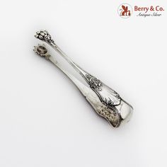 two silver spoons with designs on them sitting next to each other, one in the shape of a toothbrush