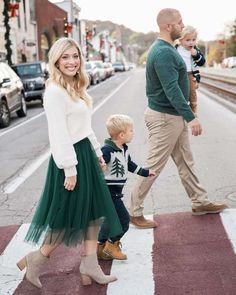 a woman and two children crossing the street in front of a man with a baby